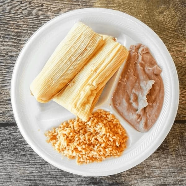 Two tamales, refried beans, and rice on a white plate from Antonio's Quick Lunch.