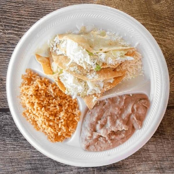 Antonio's Quick Lunch plate with three tacos, rice, and refried beans on a white divided plate.